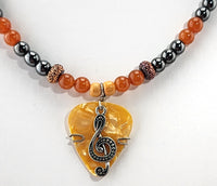 Mandarin Dreams Orange Guitar Pick Necklace with a Silver Treble Clef design on it.